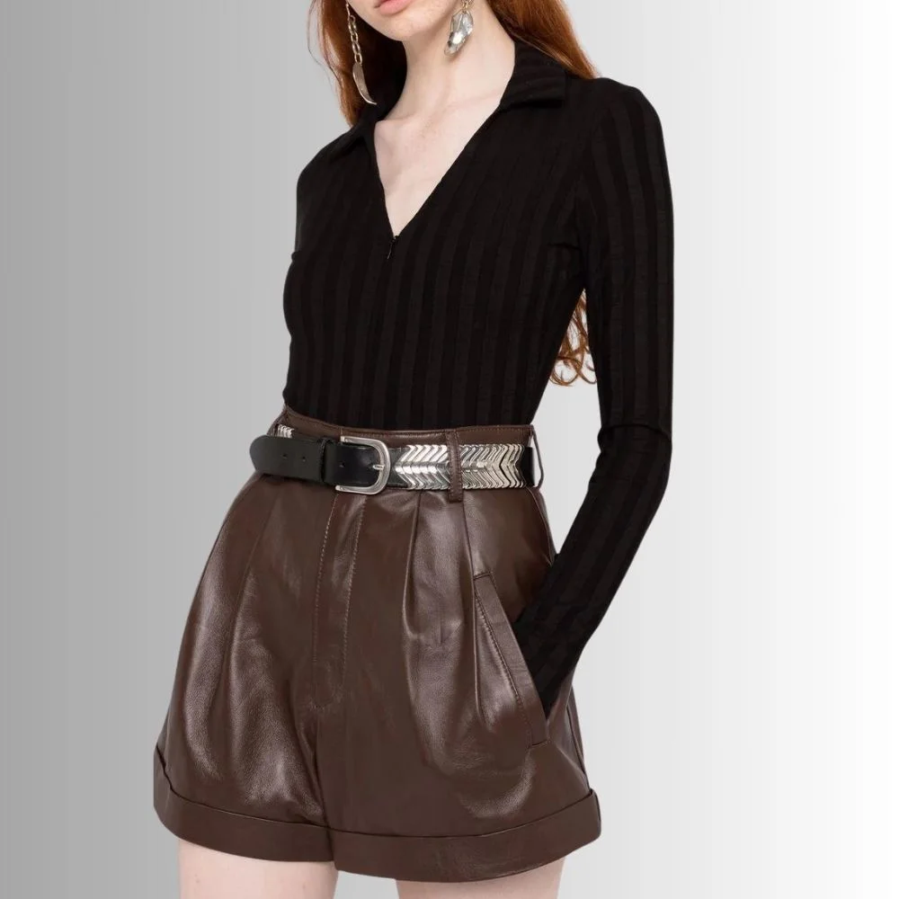 Close-up of women's brown leather shorts, highlighting rich texture and stylish pleats.